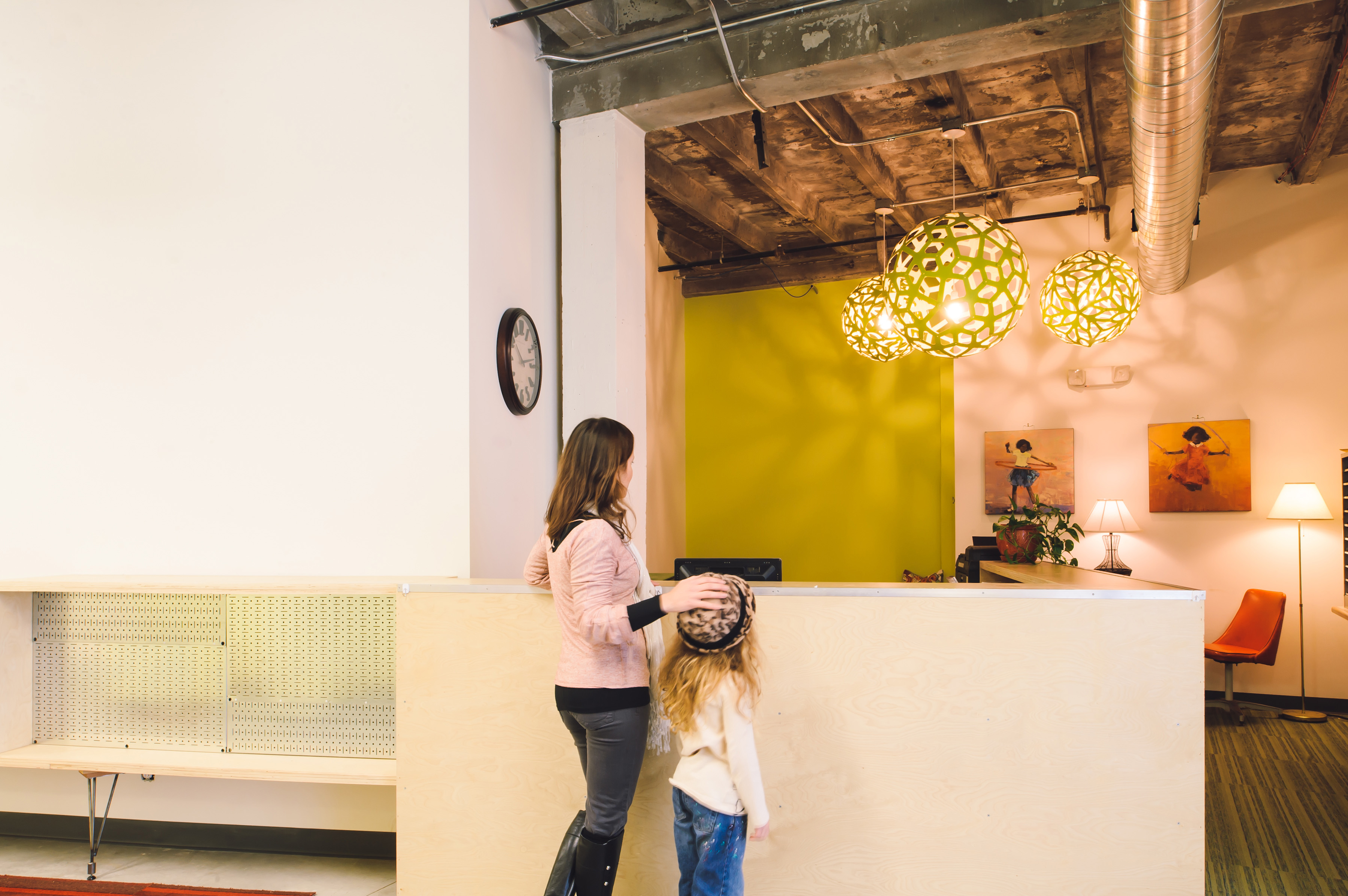 school reception, modern ceiling lights, woman with young girl, orange chair